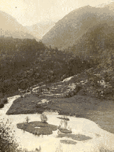 looking down on a small island in a little lake surrounded by mountains